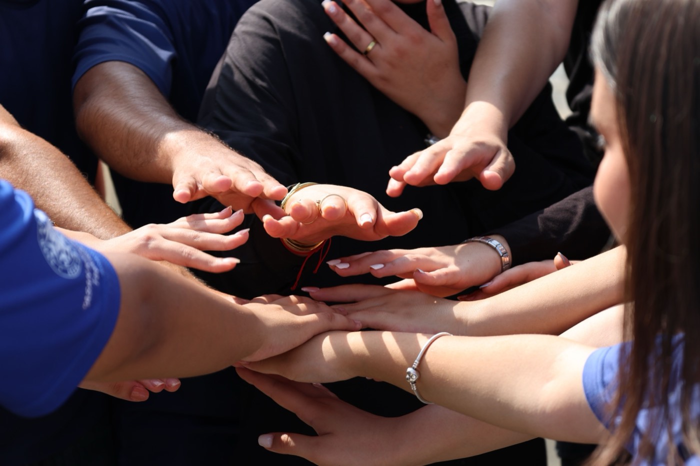 Many hands reaching into the center of a circle, stacked on top of each other