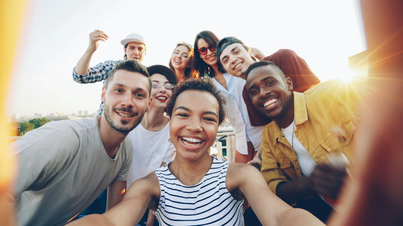 A cheerful group taking a selfie on a rooftop in the sun