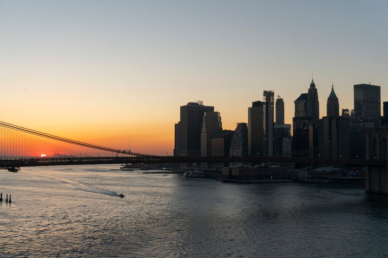 Lower Manhattan skyline and a bridge at sunset over the East River