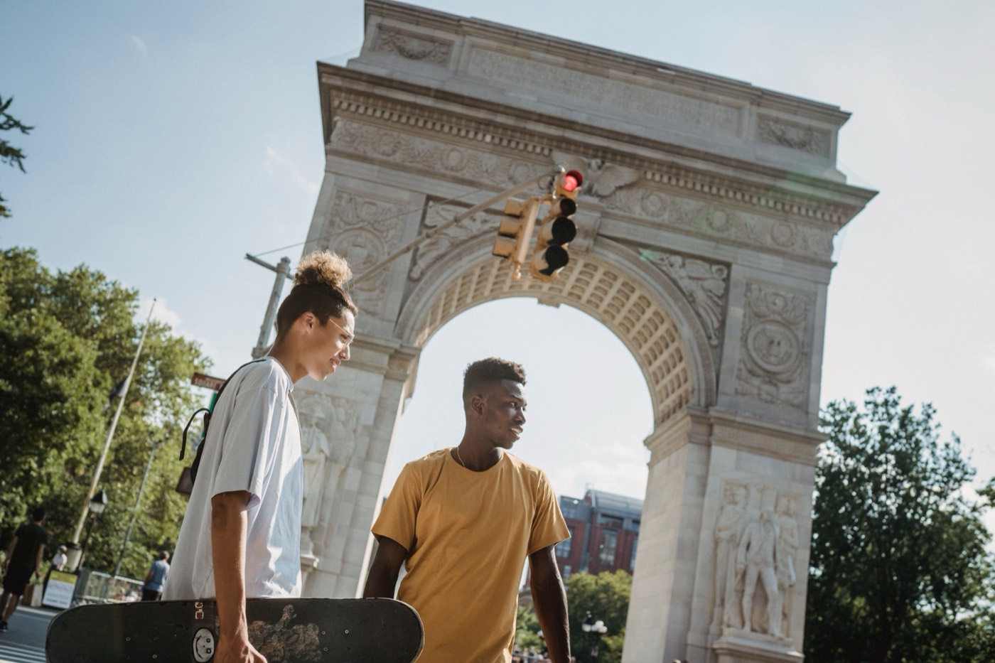 Two young men with a skateboard walking under the Washington Square Arch